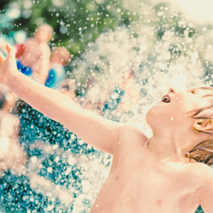2 Kid having fun with water splashing behind him