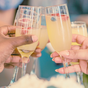 3 women clinking glasses with mimosas in hand